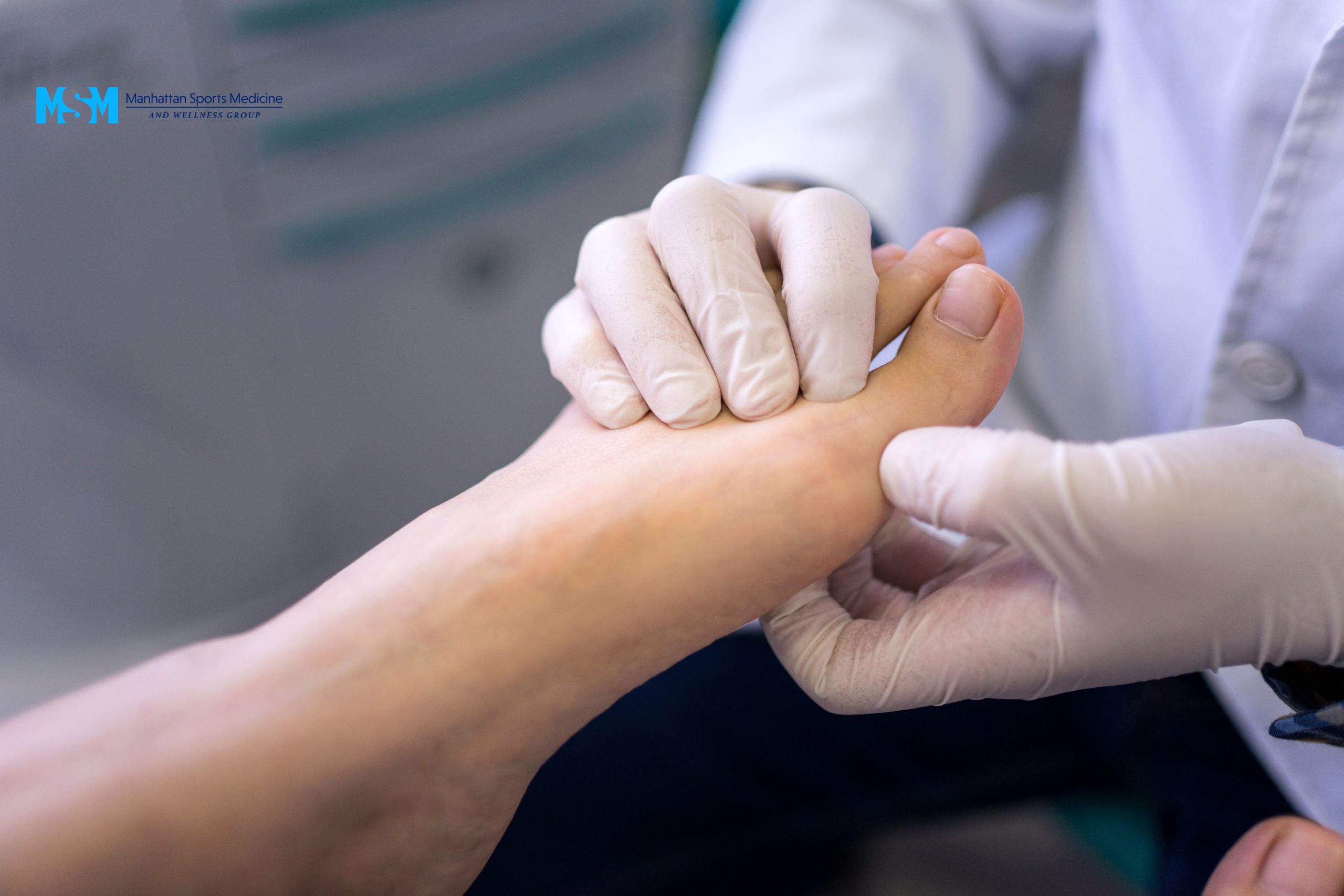 A healthcare professional wearing gloves examines a patient's foot. A healthcare professional wearing gloves examines a patient's foot