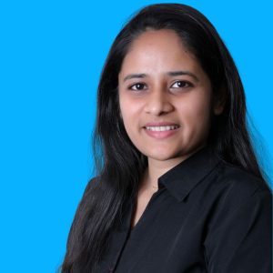 A woman with long dark hair wearing a black shirt is smiling at the camera against a solid blue background. A woman with long dark hair wearing a black shirt is smiling at the camera against a solid blue background.